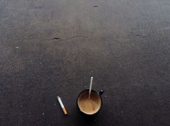 High angle view of coffee and cigarette on floor