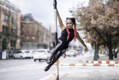 Full length of young woman exercising in city