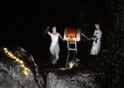 People standing by illuminated tree at night