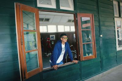 Portrait of man standing by window in building
