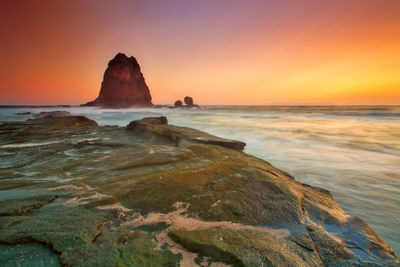 Scenic view of rocks in sea against sky during sunset