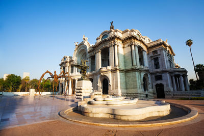 Fountain in front of building against clear blue sky