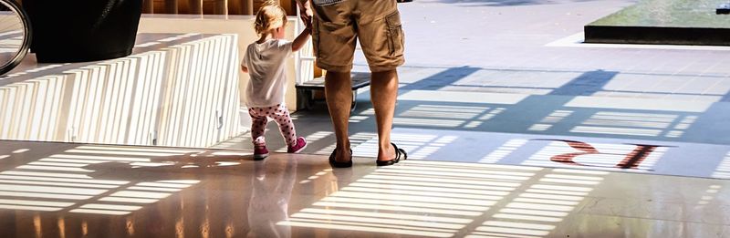 Panoramic view of man with child walking in hotel lobby