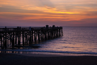 Pier over sea against sky during sunset