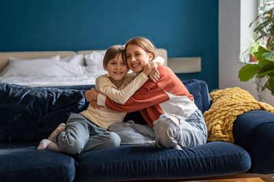 Portrait of mother and daughter sitting on sofa at home