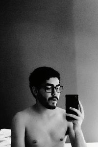 Portrait of shirtless man using mobile phone