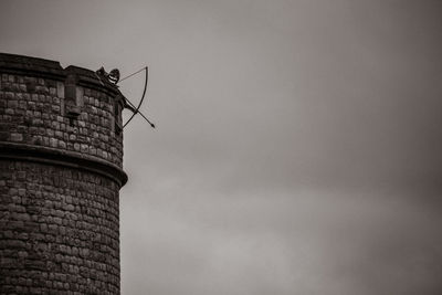 Low angle view of archery on tower against cloudy sky at dusk