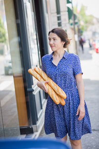 Young woman buying a french baguette