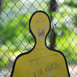 Close-up of text on human sign against chainlink fence