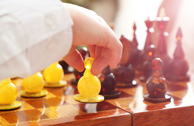 Cropped hand of person holding chess piece over board