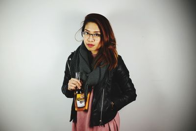 Portrait of young woman holding guitar against white background