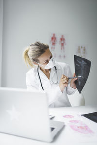 Midsection of doctor pointing at medical x-ray at clinic