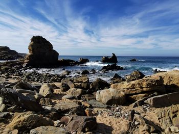 Scenic view of rocks on beach against sky