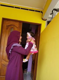 Full length of woman standing against yellow wall