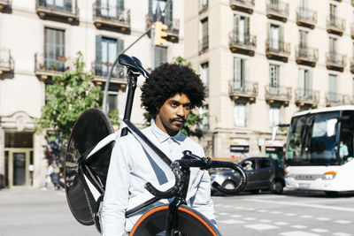 Mid adult man carrying his bicycle on his shoulders in the city