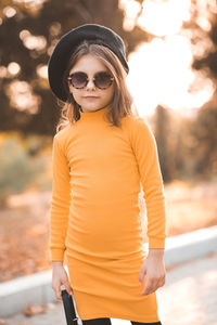 Stylish child girl 5-6 year old wear yellow dress and beret hat with glasses in autumn park outdoor
