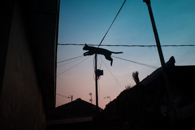 Low angle view of silhouette house against sky at dusk