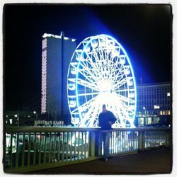 People walking on illuminated bridge at night