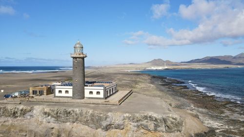 Lighthouse by sea against sky