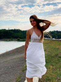 Beautiful young woman standing on land against sky