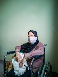 Portrait of a senior woman wearing hijab on wheelchair in a hospital.