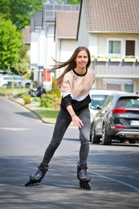 Full length of smiling woman with umbrella on road in city