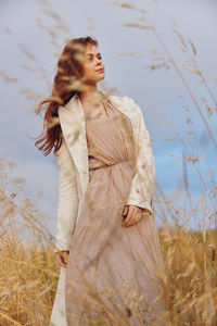 Portrait of young woman standing on field