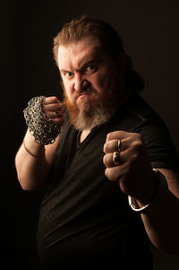 Portrait of man holding camera over black background