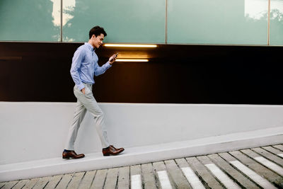 Side view of young man standing against wall