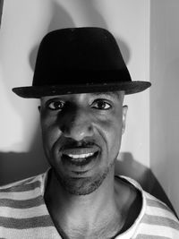 Close-up portrait of man wearing hat against wall