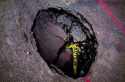 High angle view of cordon tape in hole on street