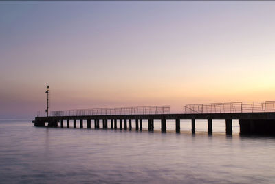 Silhouette of pier in sea during sunset