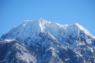 Low angle view of snowcapped mountains against clear blue sky