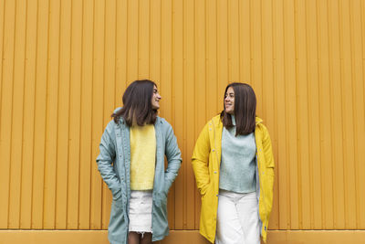 Low section of woman standing against yellow wall