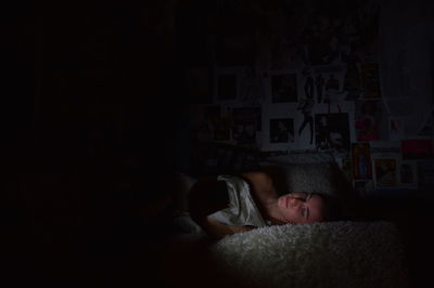 Young women lying in bed illuminated by her smartphone
