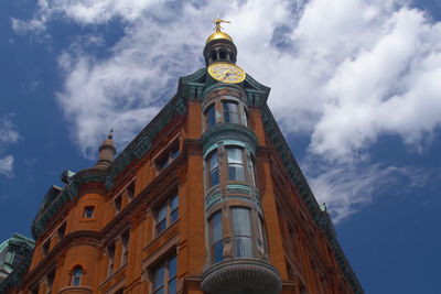 Low angle view of clock tower amidst buildings against sky