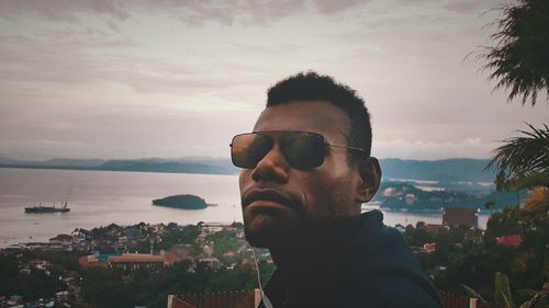 Portrait of young man in city against sky