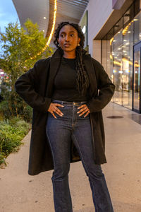 Portrait of young woman standing in city