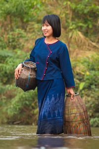 Woman with whicker baskets walking in river