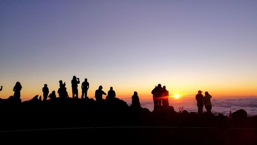 Silhouette people looking at sunset