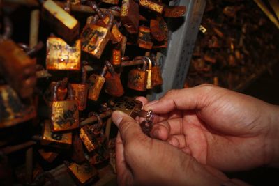 Close-up of person holding rusty padlocks