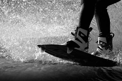 Low section of person surfboarding in sea