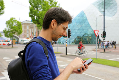 Young man using mobile phone in city