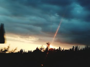 Low angle view of silhouette trees against dramatic sky