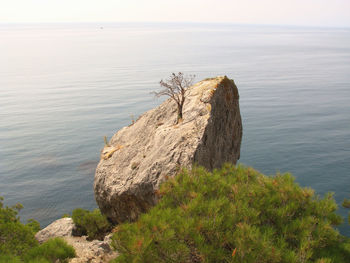 Rock formation by sea against sky