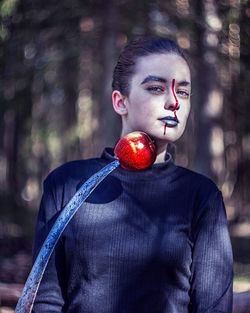 Portrait of young woman holding apple in forest