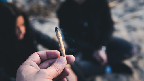 Cropped hand of woman smoking marijuana joint in city