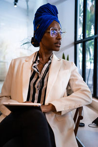 Young woman looking away while sitting on seat