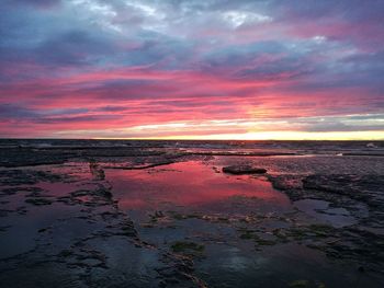 Scenic view of sea against dramatic sky during sunset