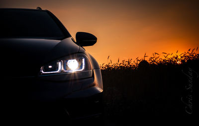 Close-up of car on field against sky during sunset